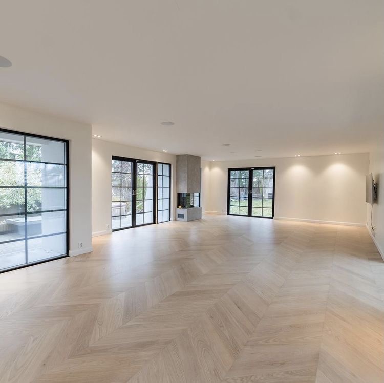 Open-plan reception room with chevron oak flooring and steel-framed garden doors